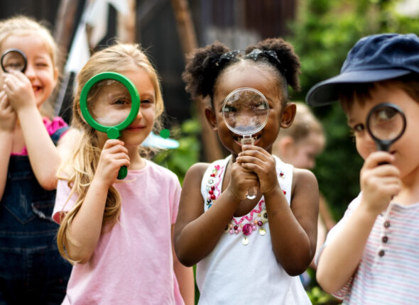 Group of kindergarten kids friends holding magnifying glass for explore