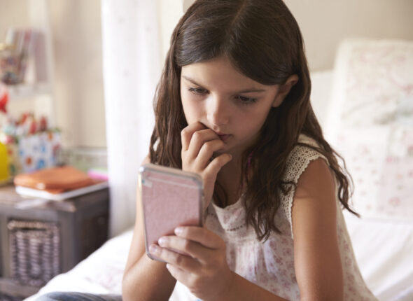 Young Girl In Bedroom Worried By Bullying Text Message